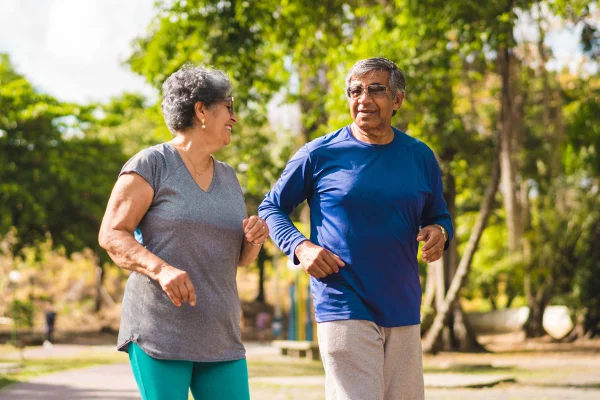 A mature couple walking briskly together along a path in a green park